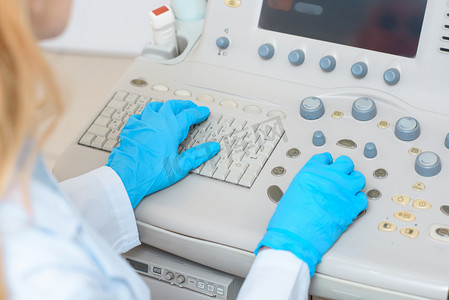 超声扫描仪在手套中的女性产科妇科医生的裁剪照片