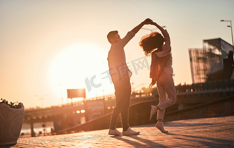 跳舞情侣摄影照片_爱在空中!可爱浪漫情侣一起在城里度过时光。英俊的大胡子男子和迷人的年轻女子恋爱了。日落时跳舞.