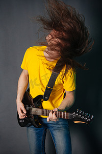 男人长着黄色 t恤衫, 玩电吉他摇滚。灰色背景下的时装工作室肖像.
