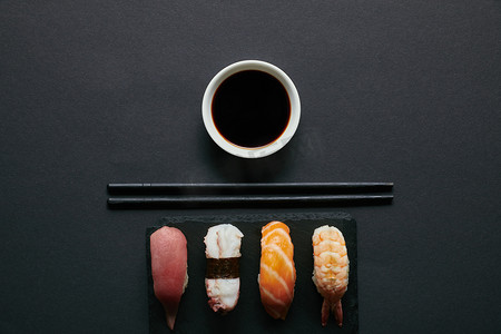 握寿司套装, 筷子和酱油在黑色板上的黑石板上的顶部视图