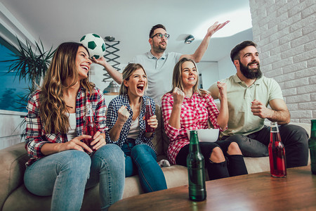 在电视上看足球、在家里庆祝胜利的快乐朋友或足球迷。友谊、体育和娱乐的概念.