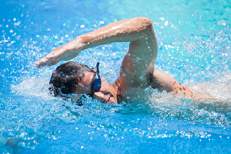 网游海报摄影照片_年轻男子在游泳池中游泳前爬网