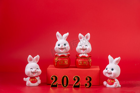兔子新年春节摄影照片_元旦2023四个兔子红色背景摆放摄影图配图