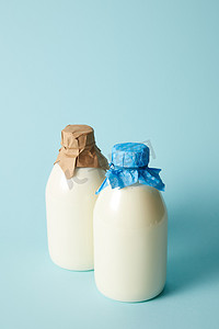 蓝色背景纸包裹两个新鲜牛奶瓶 