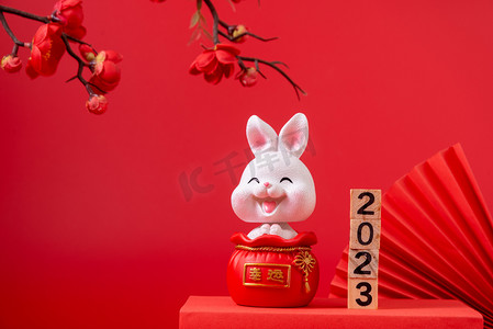 2023兔年兔子摄影照片_春节白天兔子红色背景摆放摄影图配图