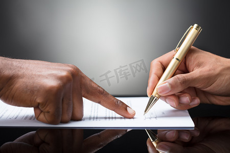 用金色的钢笔在文件前面指着一个人的手指