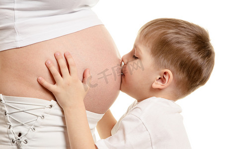 怀孕妈妈背景摄影照片_年轻的男孩接吻的怀孕的女人