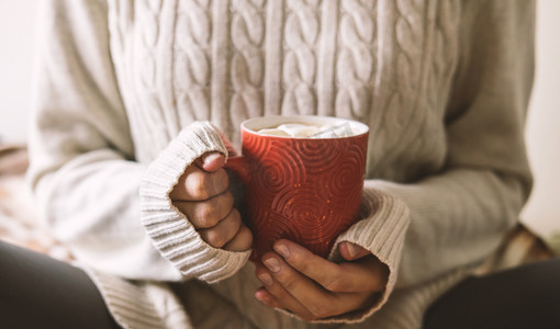 巧克力囊肿摄影照片_女性手上的毛衣是拿着一杯热咖啡, 巧克力或茶。概念冬天舒适, 早晨饮用, 温暖在冷的中间.