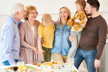 一家三代摄影照片_无忧无虑的三代六口一家站在节日餐桌上, 在家里摆姿势, 高兴地微笑着