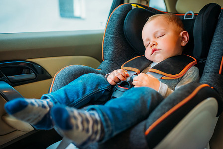 car摄影照片_可爱的小宝宝睡在儿童安全座椅汽车