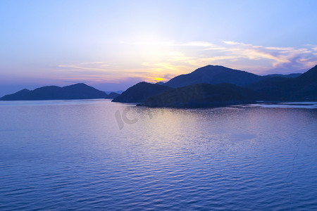 地中海风景。日落在海面上, 阳光透过云层流动明亮的彩色射线。山脉的剪影。背景