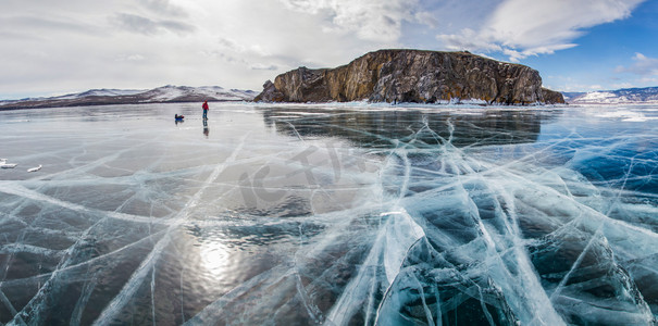 带背包的男性徒步旅行者站在冰水表面对海岸, 俄罗斯, 贝加尔湖的岩石形成 