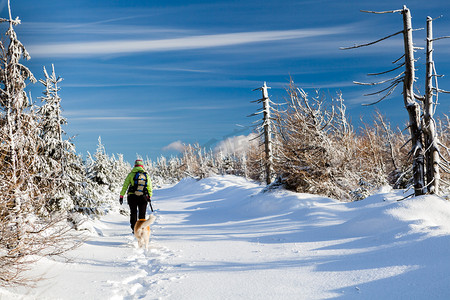 女人和狗在冬天山徒步旅行