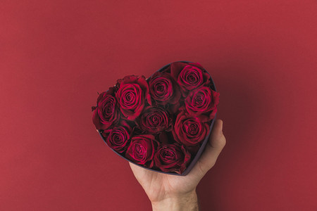 红心框摄影照片_在红色的桌面上, 情人节的概念, 在红心形框的人举行玫瑰拍摄