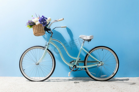 蓝色墙壁前面篮子的自行车的侧面看法与花