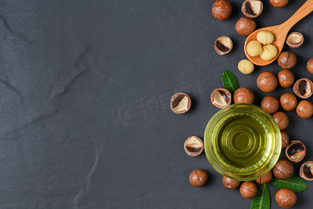 炭烧澳洲牛肋骨摄影照片_一碗澳洲坚果油和澳洲坚果在黑石头背景。超级食品健康食品理念, 顶级景观