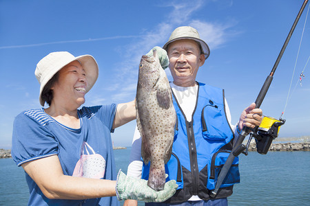 亚洲高级夫妇捕鱼和显示大石斑鱼