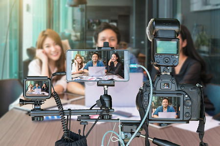 直播概念摄影照片_专业的相机与智能手机和动作摄像头的三脚架上的亚洲商界人士通过现场直播, 现场流的企业家概念