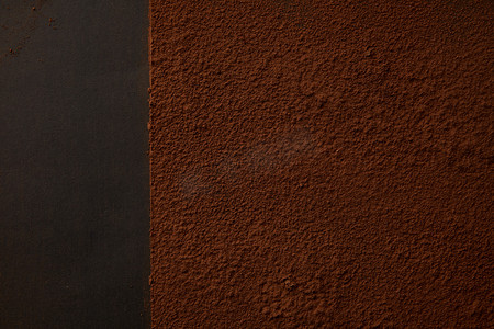 拍粉摄影照片_黑色背景上美味的棕色可可粉的顶级视图 