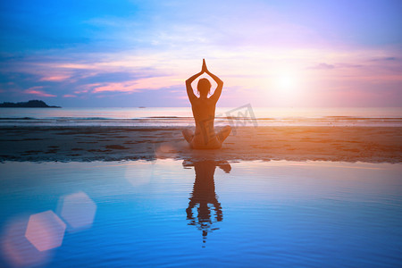默念摄影照片_剪影年轻女子在日落时练瑜伽在海滩上