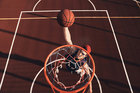 运动服装中的年轻人的最高视野在户外打篮球时得分扣篮