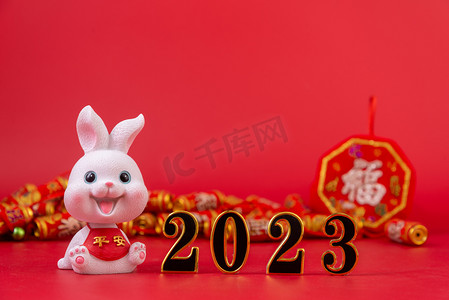 新春纳福摄影照片_新年2023兔子玩偶红色背景摆放摄影图配图