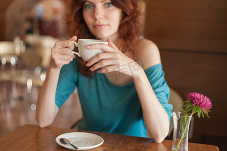 红发妇女坐在无恙，拿杯咖啡