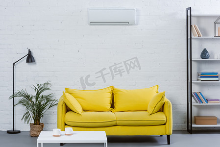 现代起居室内的黄色沙发和空调挂在白墙上
