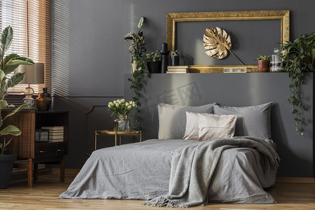 深色房间内的灰色床上用品和毯子墙上空框装饰金叶