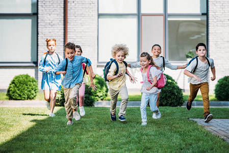 绿女孩摄影照片_一群可爱的小学生在学校花园里奔跑