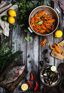 各种美味的海鲜与柠檬和草药在乡村木桌上的顶视图 