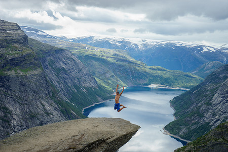 海怪摄影照片_年轻人跳在边缘 Trolltunga。挪威