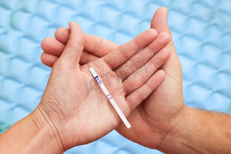 女性和男性的手里拿着一个积极的怀孕测试。两条线上的测试