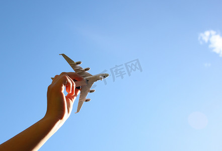 过滤器摄影照片_女子手牵着玩具飞机在蓝天和云彩的映衬下的近照