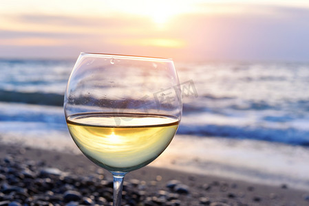 浪漫 glass 的酒坐在沙滩上多彩夕阳眼镜的反对日落，白葡萄酒白葡萄酒与云天空背景