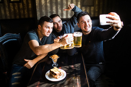 快乐的男性朋友拍照并喝啤酒在酒吧或酒吧派对