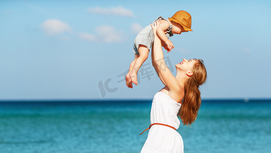 渺小摄影照片_快乐家庭母亲和婴儿的儿子走过海洋总和在海滩上