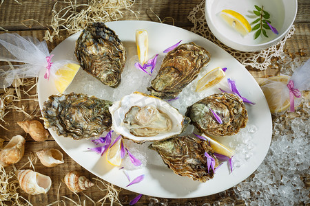 关于古董牡蛎刀碎的冰和柠檬水果和珍珠在大理石板镀锡板银叉子的牡蛎。打开金属铜板上深色木制背景上的牡蛎.