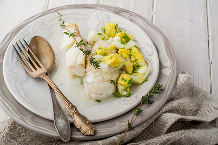 咸蛋黄摄影照片_白色的水煮的鱼鳕鱼配酱基于黄油和煮鸡蛋