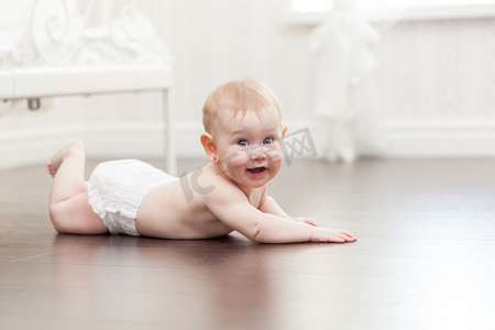 婴儿在行动摄影照片_快乐七个月大女婴在硬木地板上爬