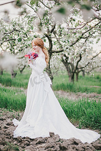 美丽的新娘在老式的婚纱摆在盛开的苹果花园