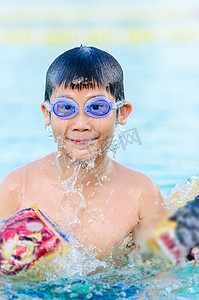 亚洲男孩戴着眼镜在池中有乐趣.