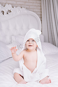 婴儿躺在床上的白毛巾 adorably。快乐的童年和医疗保健概念.