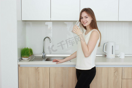 矿产探测摄影照片_年轻女子在厨房喝水