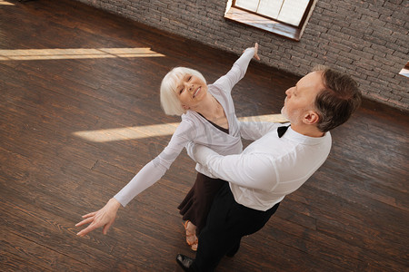 乐观的退休跳舞夫妇享受华尔兹舞蹈工作室
