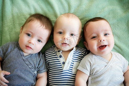 双胞胎婴儿摄影照片_肖像的新生三胞胎正躺在床上