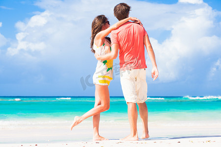 后视图的幸福浪漫的年轻情侣在沙滩上拥抱