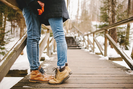 在冬季公园的木制楼梯上接吻的时髦夫妇