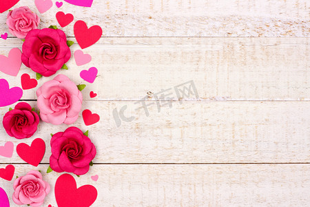 情人节侧边红色和粉红色的纸心和玫瑰对一个质朴的白色木材背景与复制空间.