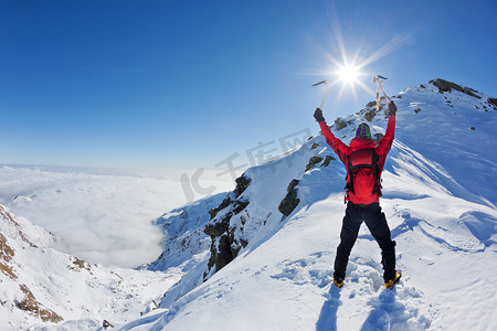登山运动员到达顶部的雪山在阳光明媚的冬天